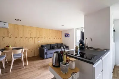 a kitchen and living room with a couch and a table at Via Alpina Apartments with sauna in Mojstrana