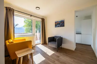 a living room with a chair and a window at Via Alpina Apartments with sauna in Mojstrana