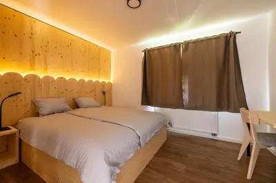 a bedroom with a bed with a wooden wall at Via Alpina Apartments with sauna in Mojstrana