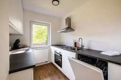 a kitchen with white counters and a sink and a window at Via Alpina Apartments with sauna in Mojstrana