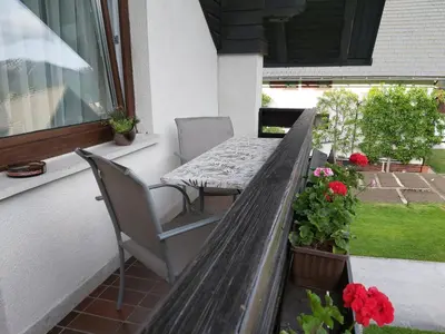 a wooden table and chairs on a porch with flowers at Apartment Šporar in Bohinj