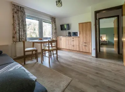 a living room with a bed and a table with chairs at Apartment Šporar in Bohinj