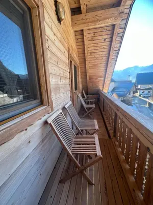 a porch of a cabin with two chairs on it at Apartmaji Katrnjek in Bohinj