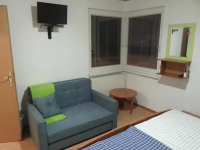 a living room with a blue couch and a television at Apartmaji in sobe Kocjančič in Podčetrtek