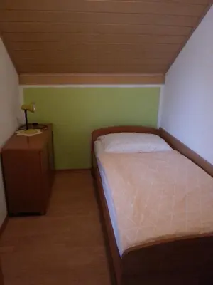 a small bedroom with a bed and a night stand at Apartmaji in sobe Kocjančič in Podčetrtek
