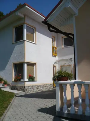 a white house with two windows and a balcony at Apartmaji in sobe Kocjančič in Podčetrtek