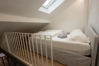 a white crib in a room with a ceiling at Karlovška Duplex Urban Apartment in Ljubljana