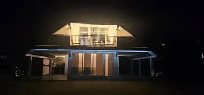 a house lit up at night with a balcony at Apartment ZOI in Ptuj