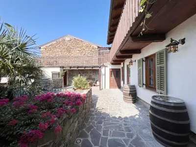 a courtyard of a house with flowers and a barrel at Rural Family Escape in Vipava