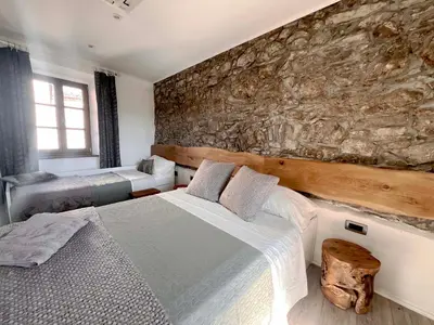 a bedroom with two beds and a stone wall at Rural Family Escape in Vipava