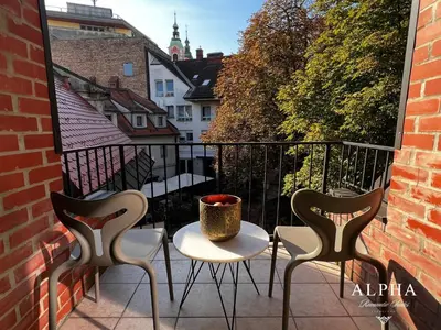 a balcony with three chairs and a table with a vase on it at Alpha Romantic Suites Ljubljana in Ljubljana
