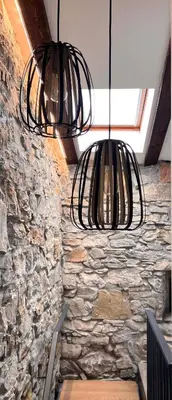 two black metal lights hanging from a stone wall at Tranquil Escape in Vipava