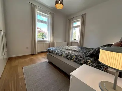 a bedroom with a bed and two windows at Luxury Apartment Privoz in Ljubljana