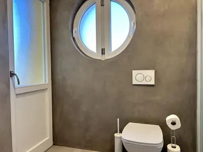 a bathroom with a toilet and a round window at Luxury Apartment Privoz in Ljubljana