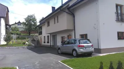 a silver car parked in a parking lot next to a building at Tourist farm Megušar in Škofja Loka