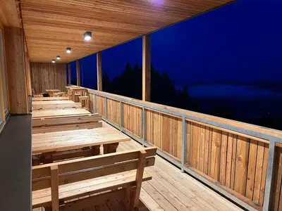 a row of wooden benches on a deck at night at Mozirska koča in Mozirje