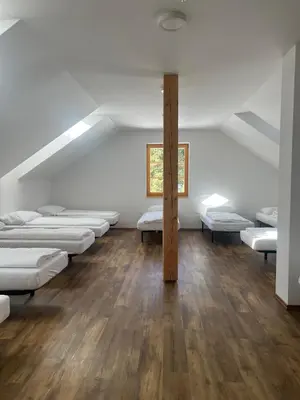 a room with rows of mattresses and a window at Mozirska koča in Mozirje