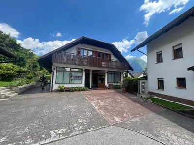 a house with a balcony on top of a driveway at Apartments and Rooms Tajcr in Bovec