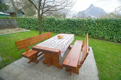 two wooden benches and a picnic table in a yard at Apartments and Rooms Tajcr in Bovec