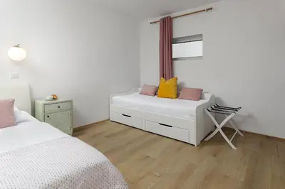 a bedroom with a white couch and a chair at Cozy house close to Ljubljana center in Ljubljana