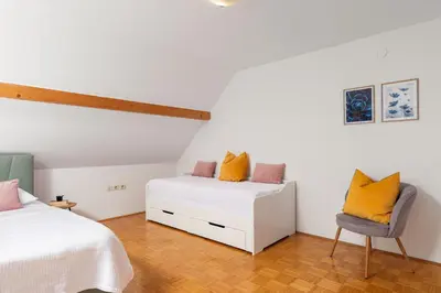 a bedroom with two beds and a chair at Cozy house close to Ljubljana center in Ljubljana
