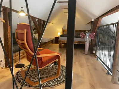 a living room with a chair and a bed at Hiša Galeria in Loče pri Poljčanah