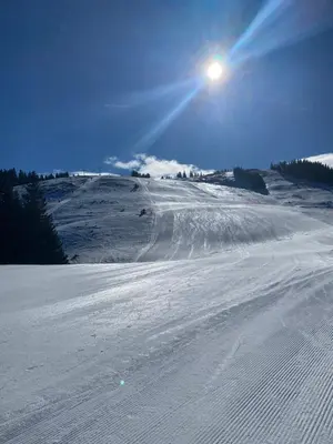 a snow covered slope with the sun in the sky at Alpine Escape Golte Apartment in Mozirje