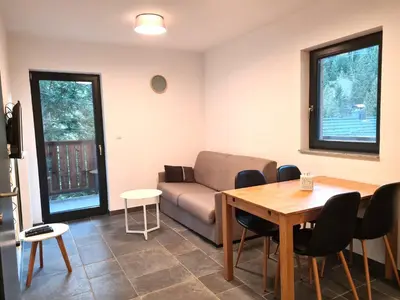 a living room with a couch and a table and chairs at Alpine Escape Golte Apartment in Mozirje