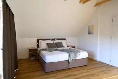 a bedroom with a bed with white sheets and wood floors at Hiša Janko in Dolenjske Toplice