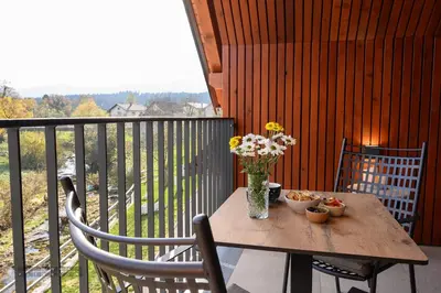 a wooden table with a vase of flowers on a balcony at Hiša Janko in Dolenjske Toplice