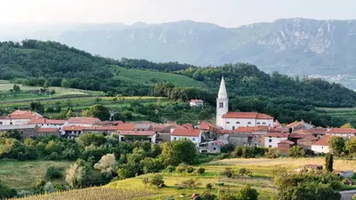 a town in a valley with a church and mountains at Historic Wine-Stone House in Vipava
