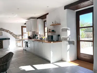 a kitchen with white cabinets and a large window at Historic Wine-Stone House in Vipava