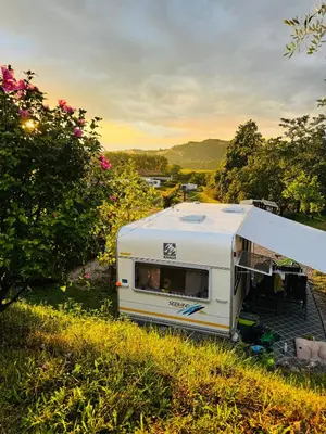 a white trailer parked in a field with trees at Saxida Wine & Camping Resort Pitches in Dornberk