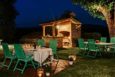 a table and chairs in a backyard with a fireplace at Opulent Villa with Sauna in the Heart of Karst in Dutovlje