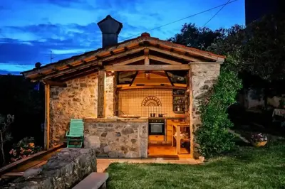 a stone house with a kitchen in a yard at Opulent Villa with Sauna in the Heart of Karst in Dutovlje