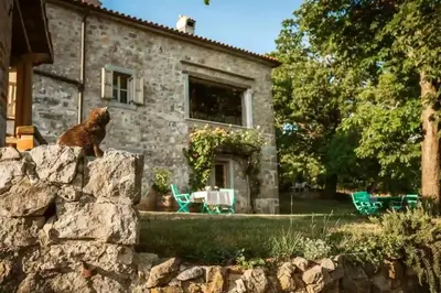 a cat sitting on a wall in front of a stone house at Opulent Villa with Sauna in the Heart of Karst in Dutovlje