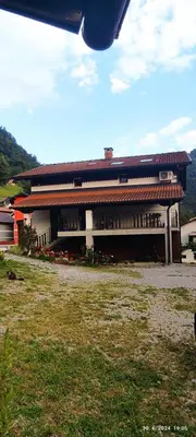 a building with a red roof and a grass field at Apartma SOFIA in Tolmin