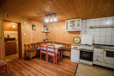 a kitchen with wooden walls and a table and chairs at Cottage of Rising Sun in Goreljek