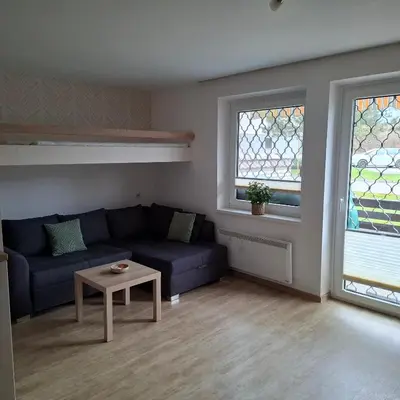 a living room with a blue couch and two windows at Bohinj Planika J2 in Bohinj