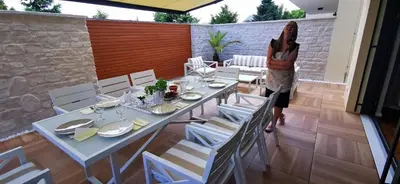 a woman standing in front of a table and chairs at Sončna oaza - Vila Melita in Moravske Toplice