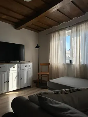 a bedroom with a bed and a tv and a window at Hiška pri Paulu in Dobrovnik