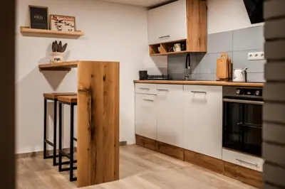 a kitchen with white cabinets and a wooden counter top at Hiška pri Paulu in Dobrovnik