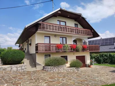 a house with a balcony with red flowers on it at Spacious Countryside Flat - 25 minutes from Ljubljana in Grosuplje