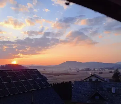 a sunset with a view of a farm with solar panels at Spacious Countryside Flat - 25 minutes from Ljubljana in Grosuplje