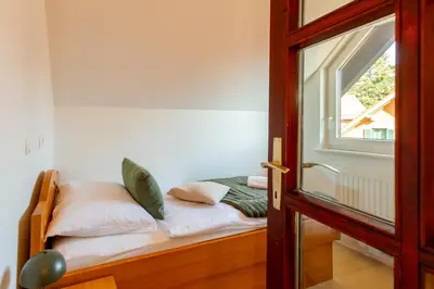 a bed with pillows on it next to a window at Pohorski Dom in Pohorje