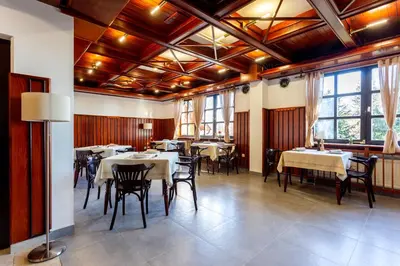 a dining room with tables and chairs and windows at Pohorski Dom in Pohorje