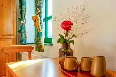 a vase with a rose in it sitting on a table at Pohorski Dom in Pohorje