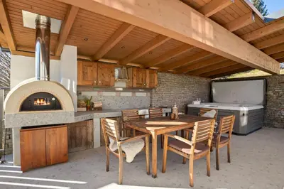 an outdoor kitchen with a wooden table and chairs at Wellness Chalet close to Ljubljana in Rakitna