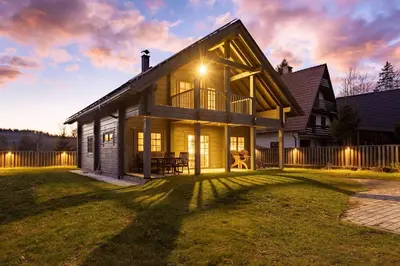 a house on a lawn with a sunset at Wellness Chalet close to Ljubljana in Rakitna
