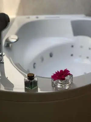 a bath tub with two candles and a pink flower at eco boutique hotel AMS Beagle in Bled